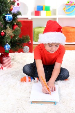 Noel Baba şapkalı küçük çocuk Noel Baba'ya mektup yazar