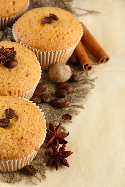 Tasty muffin cakes on burlap, spices and coffee seeds, on beige background — Stock Photo, Image