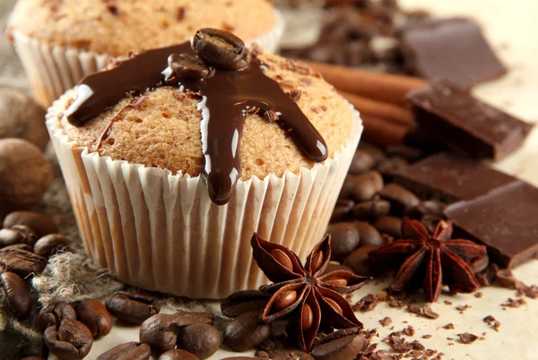 Tasty muffin cakes with chocolate, spices and coffee seeds, close up — Stock Photo, Image