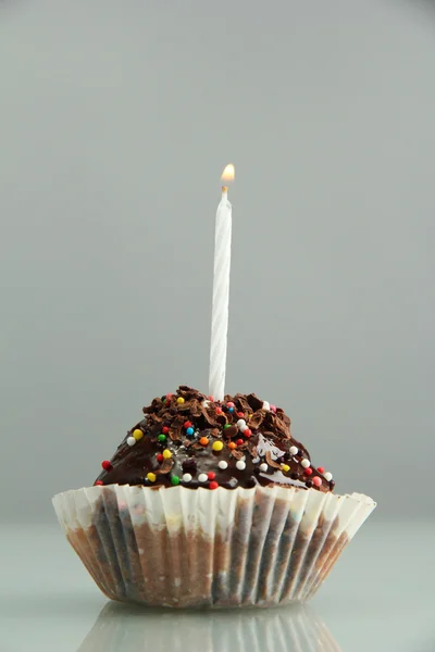 キャンドル付きおいしい誕生日カップケーキ,グレーの背景に — ストック写真