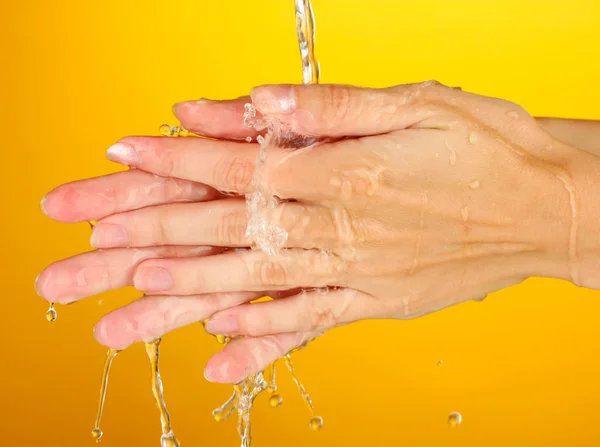 Lavarse las manos sobre fondo naranja de cerca — Foto de Stock