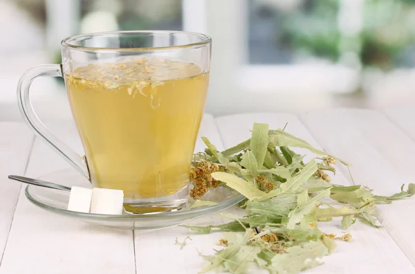 Tazza di tè di vetro con tiglio su tavolo di legno su sfondo finestra — Foto Stock