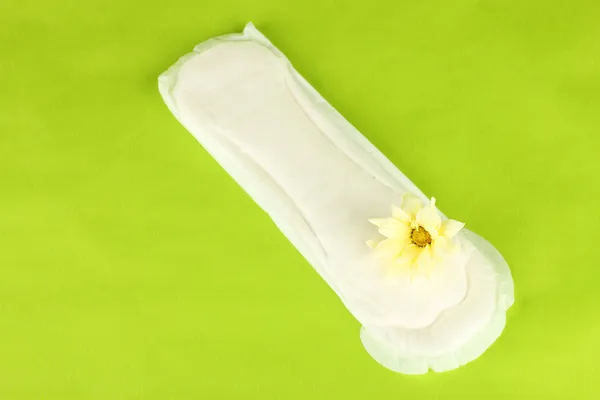 Panty liner and yellow flower on green background close-up — Stock Photo, Image