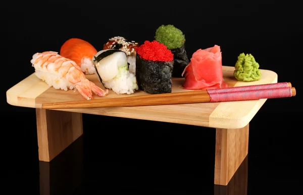 Delicioso sushi servido en tablero de madera aislado en negro — Foto de Stock