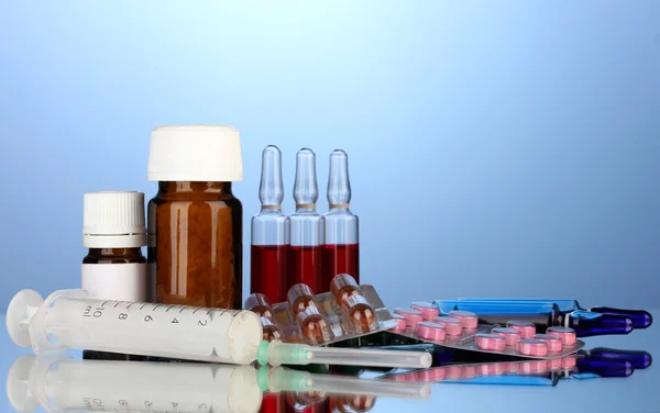 Medical ampules, bottles, pills and syringes on blue background — Stock Photo, Image