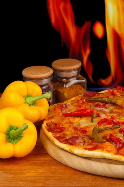 与火焰背景上的木制板上蔬菜美味意大利辣香肠比萨饼 — 图库照片