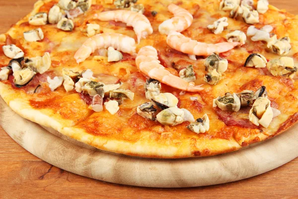 Delicious pizza with seafood on stand on wooden background — Stock Photo, Image