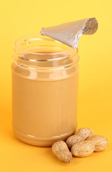 Delicious peanut butter in open jar of peanut near on yellow background — Stock Photo, Image
