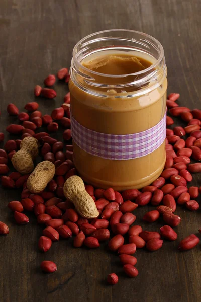 Delicious peanut butter in jar on wooden table close-up — Stock Photo, Image