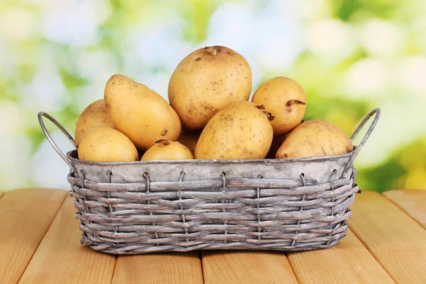 Batatas maduras na cesta na mesa de madeira no fundo natural — Fotografia de Stock
