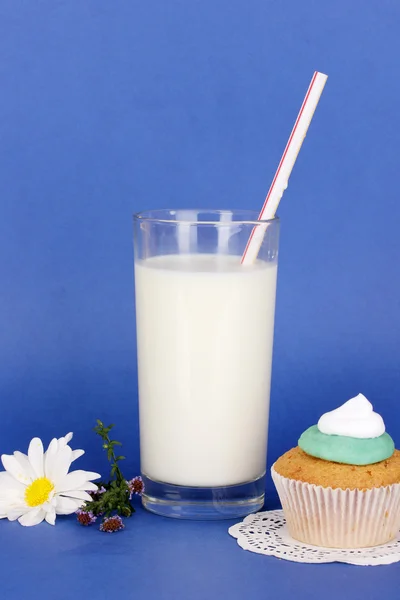 Glass of fresh new milk with cake on blue background — Stock Photo, Image