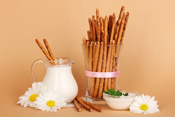 Tasty crispy sticks in glass cup on beige background — Stock Photo, Image