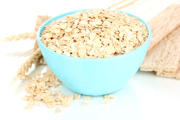 Blue bowl full of oat flakes with spikelets and oat biscuits isolated on white — Stock Photo, Image