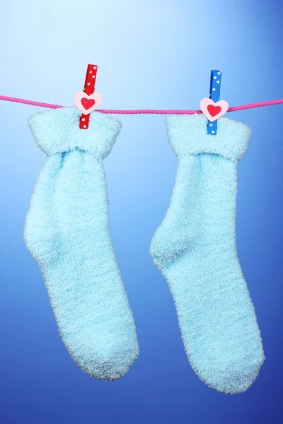 Pair of blue socks hanging to dry over blue background — Stock Photo, Image