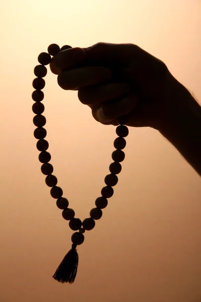 Male hand with rosary, on brown background — Stock Photo, Image