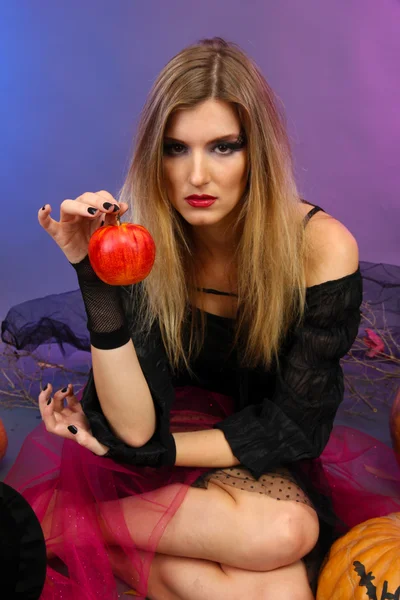 Halloween-Hexe mit rotem Apfel auf farbigem Hintergrund — Stockfoto