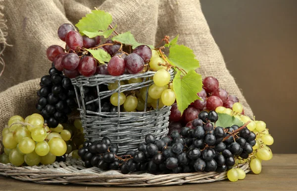 熟透的甜葡萄在篮子里，棕色背景上的分类 — 图库照片