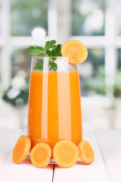 Vidro de suco de cenoura na mesa de madeira, no fundo da janela — Fotografia de Stock