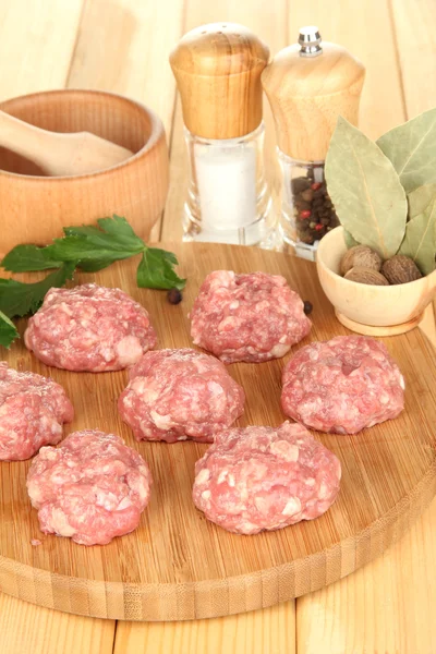 Raw meatballs with spices on wooden table — Stock Photo, Image