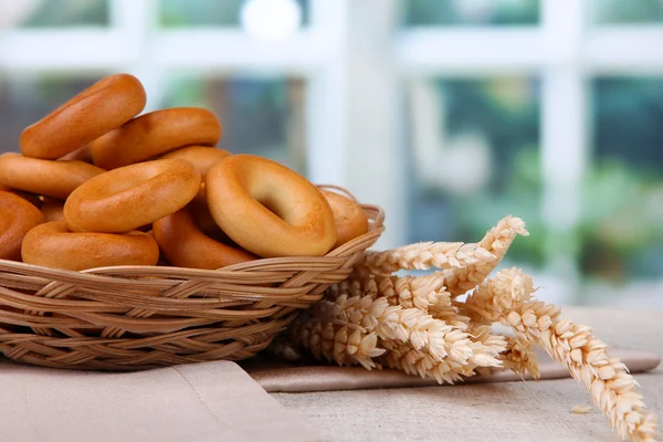 Tasty bagels in basket and spikelets on table — Stock Photo, Image