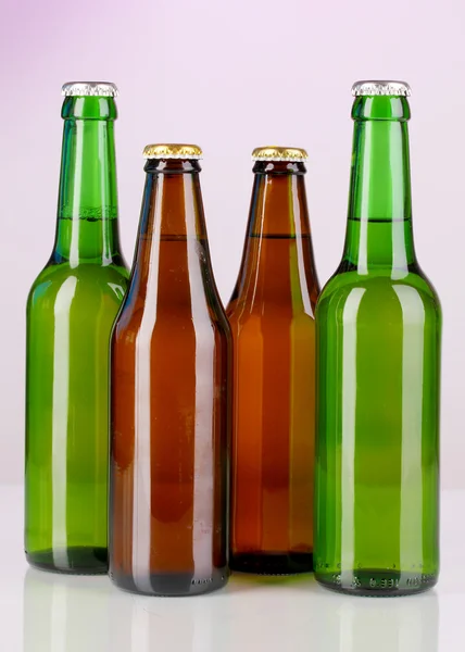 Bottiglie di birra in vetro colorato su sfondo viola — Foto Stock