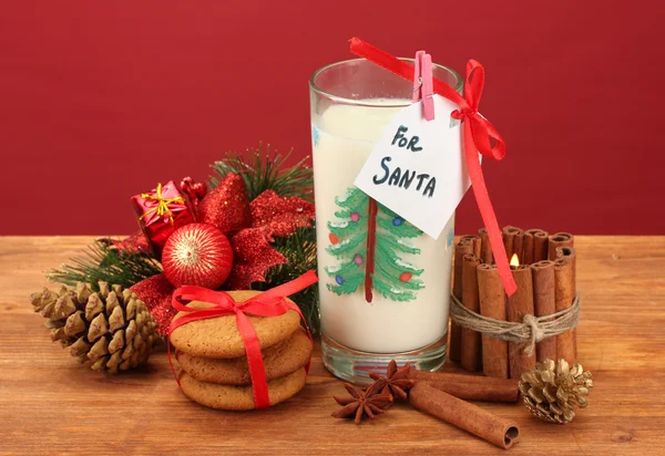 Cookies voor santa: Conceptuele afbeelding van gember koekjes, melk en kerst decoratie op rode achtergrond — Stockfoto