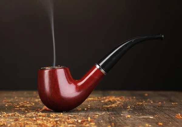 Smoking pipe and tobacco on wooden table on black background — Stock Photo, Image