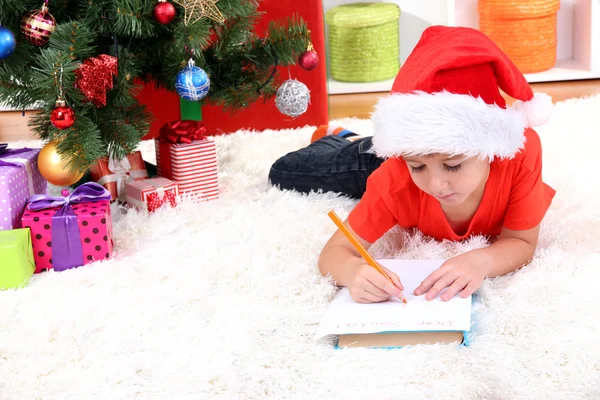 Kleine jongen in Kerstman hoed schrijft een brief aan de Kerstman — Stockfoto