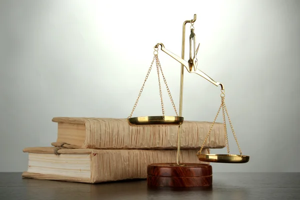 Gold scales of justice and books on grey background — Stock Photo, Image