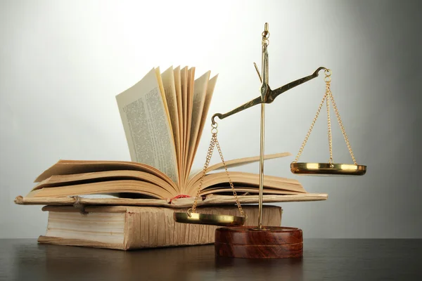 Gold scales of justice and books on grey background — Stock Photo, Image