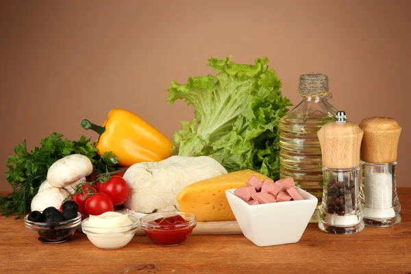 Ingredienser för pizza på träbord på brun bakgrund — Stockfoto