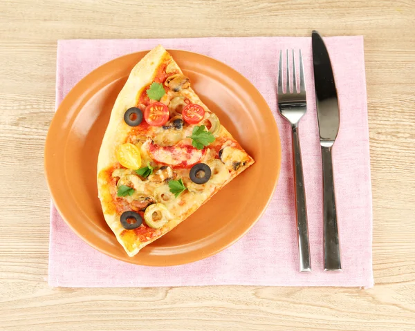 Plate with a slice of delicious pizza on wooden background Stock Photo