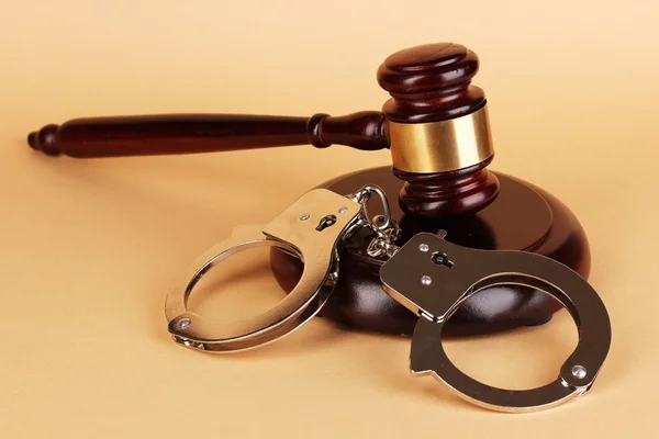 Gavel and handcuffs on beige background Stock Picture