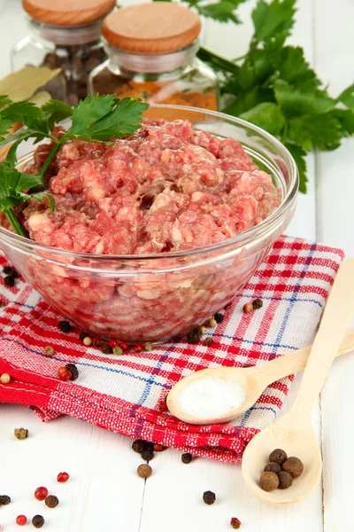 Bowl of raw ground meat with spices on wooden table Royalty Free Stock Images