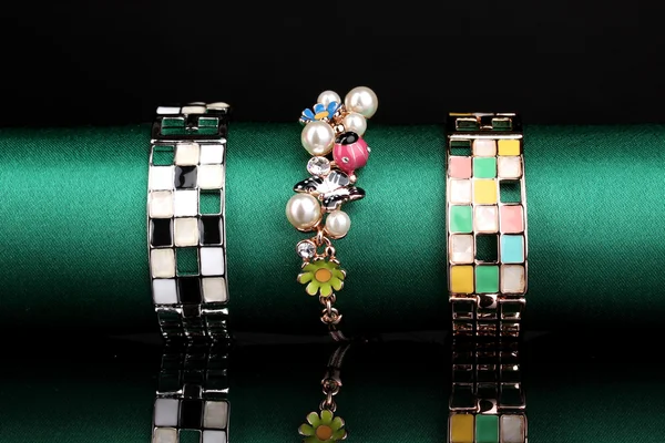 Tres pulseras de moda sobre tela verde sobre fondo negro —  Fotos de Stock