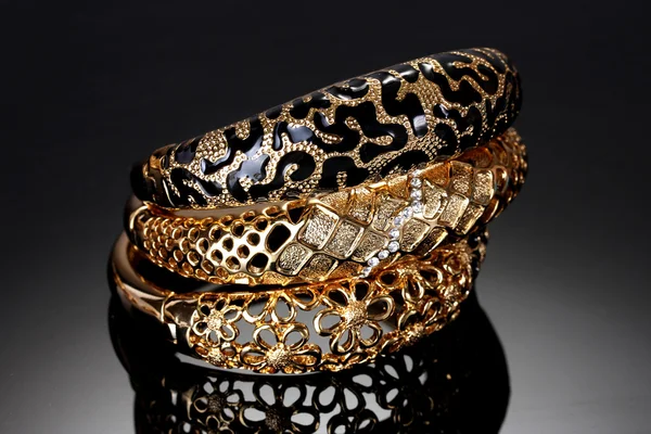 Belas pulseiras douradas no fundo cinza — Fotografia de Stock