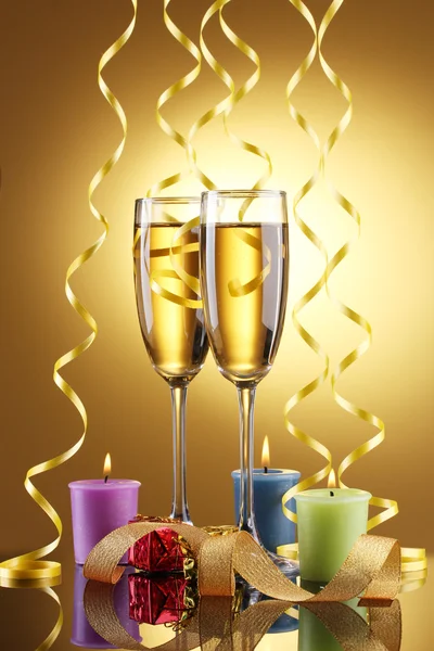 香槟、 蜡烛、 礼品和在黄色背景上的流光的眼镜 — 图库照片