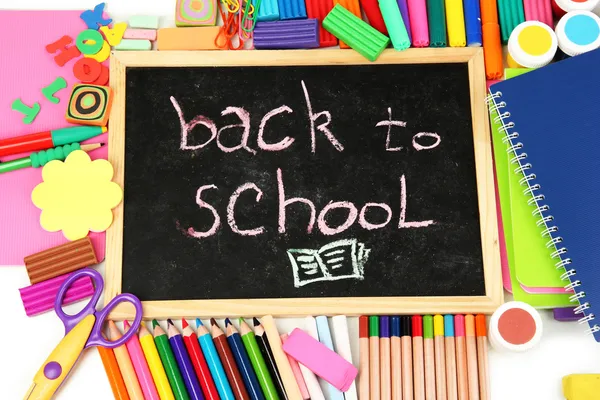 Les mots "Retour à l'école" écrits à la craie sur le petit bureau de l'école avec divers fournitures scolaires close-up — Photo