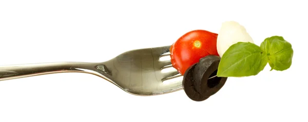 Queso mozzarella con verduras en un tenedor sobre fondo blanco de cerca — Foto de Stock