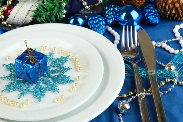 Small Christmas gift on plate on serving Christmas table in blue tone close-up — Stock Photo, Image