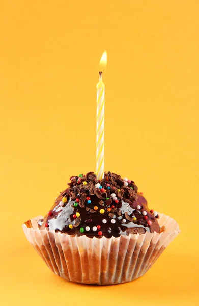 オレンジ色の背景上の蝋燭とおいしい誕生日カップケーキ — ストック写真