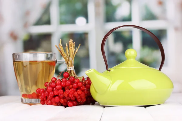 Tè con viburno rosso sul tavolo su sfondo luminoso — Foto Stock