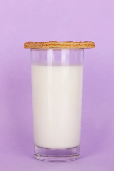 Verre de lait frais neuf avec biscuits sur fond violet — Photo