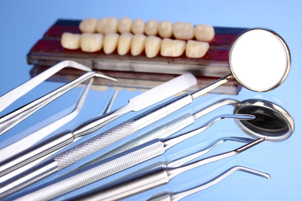 Conjunto de ferramentas dentárias com dentadura em fundo azul — Fotografia de Stock