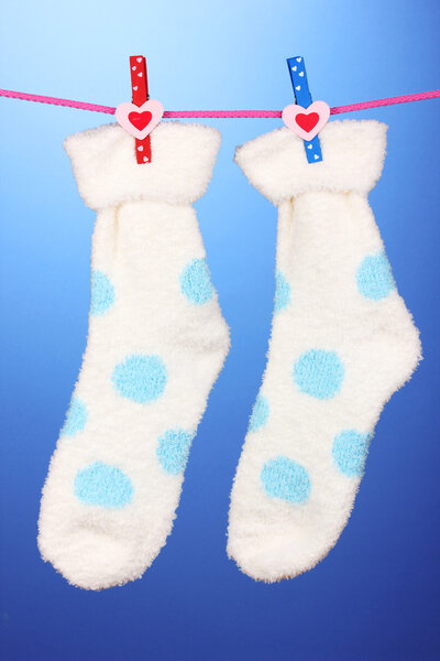 Pair of socks with polka dots hanging to dry over blue background