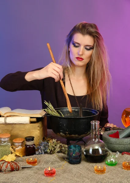 Halloween čarodějnice připravuje jed polévka v ní kotel na barvu pozadí — Stock fotografie