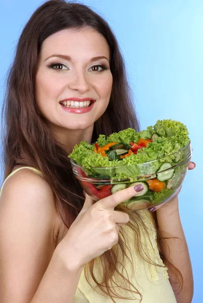 Beautiful woman with vegetable salad on blue background — Stock Photo, Image