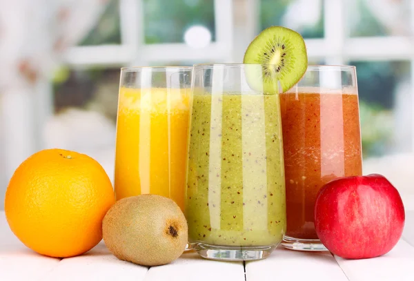 Zumos de frutas frescas sobre mesa de madera, sobre fondo de ventana — Foto de Stock