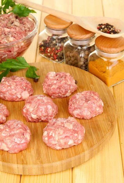 Raw meatballs with spices on wooden table — Stock Photo, Image
