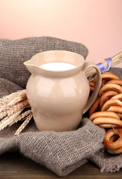 Tarro de leche, sabrosos bagels y espiguillas sobre mesa de madera, sobre fondo marrón —  Fotos de Stock